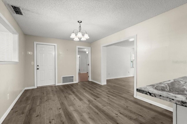unfurnished dining area with wood finished floors, visible vents, and an inviting chandelier