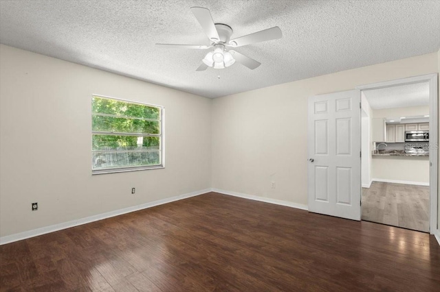 unfurnished room featuring baseboards, wood finished floors, a textured ceiling, and ceiling fan