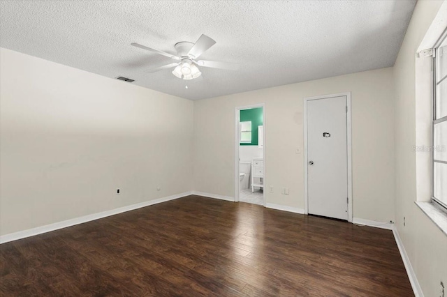 empty room with wood finished floors, visible vents, baseboards, a textured ceiling, and ceiling fan