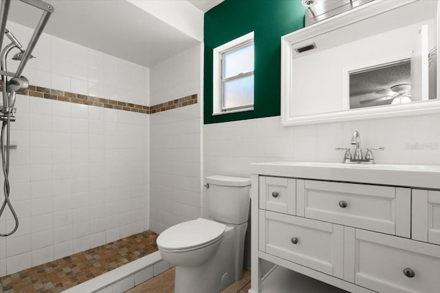 full bath featuring vanity, tile walls, a tile shower, toilet, and visible vents