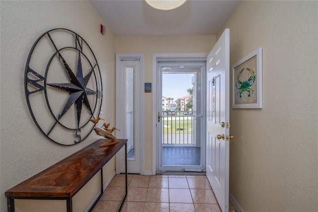 entryway with a textured wall, baseboards, and light tile patterned floors