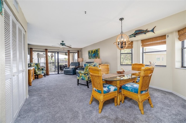 dining area featuring ceiling fan with notable chandelier and carpet