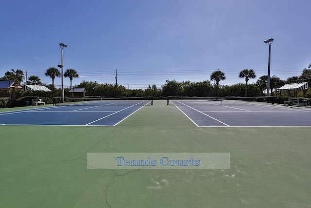 view of tennis court with community basketball court and fence