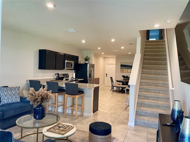 living room with visible vents, recessed lighting, stairway, and light tile patterned flooring