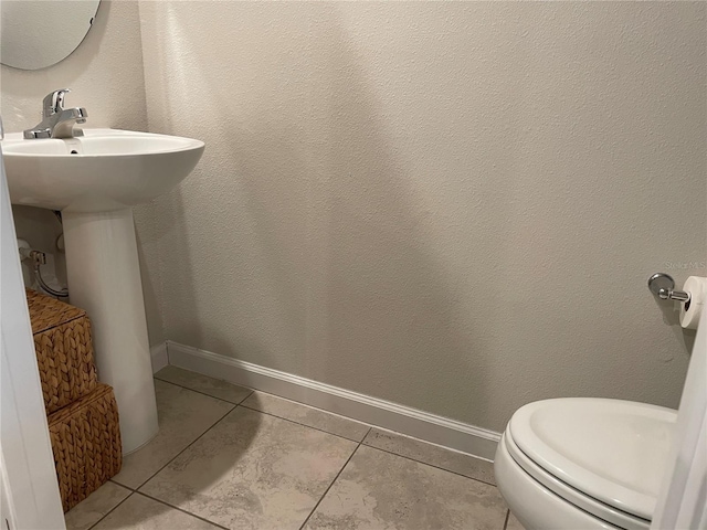 bathroom with baseboards, a sink, tile patterned flooring, and toilet