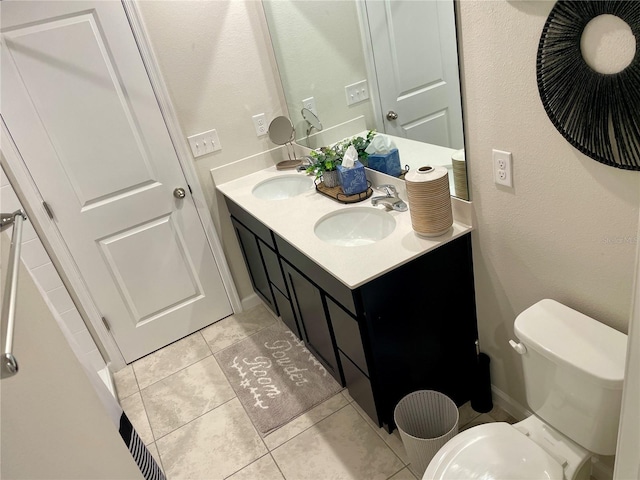 bathroom featuring double vanity, tile patterned floors, toilet, and a sink