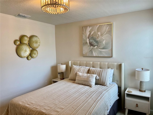 bedroom featuring a chandelier, visible vents, and a textured ceiling
