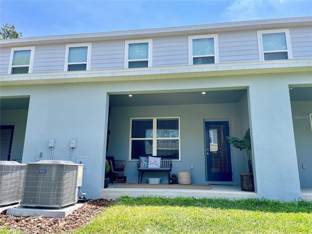 rear view of property with central AC, a porch, and stucco siding