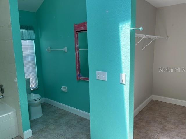 2091 Maltese Ln, New Smyrna Beach, FL 32168 - bathroom with tile patterned flooring, baseboards, toilet, and tiled tub