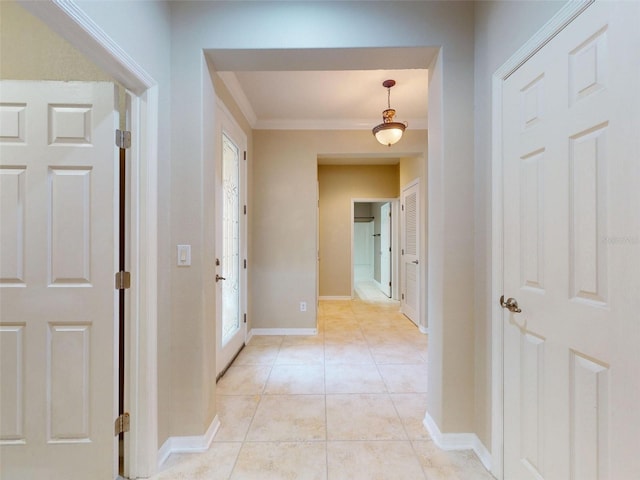 corridor with crown molding, baseboards, and light tile patterned floors