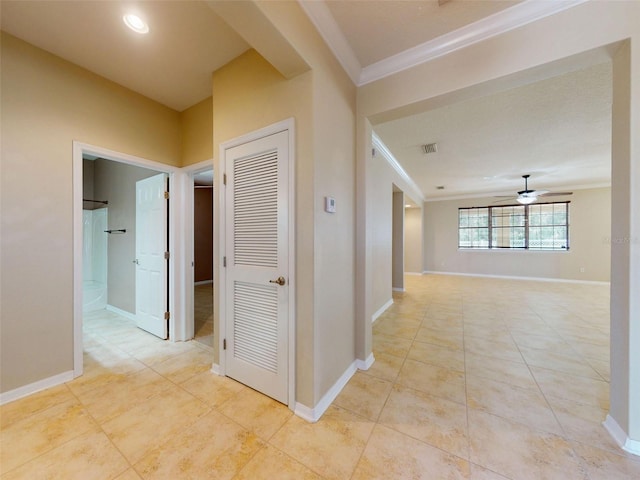 corridor featuring visible vents, ornamental molding, baseboards, and light tile patterned floors