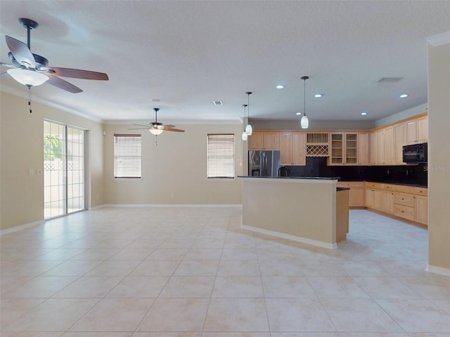 kitchen featuring plenty of natural light, black microwave, open floor plan, stainless steel fridge, and light brown cabinets
