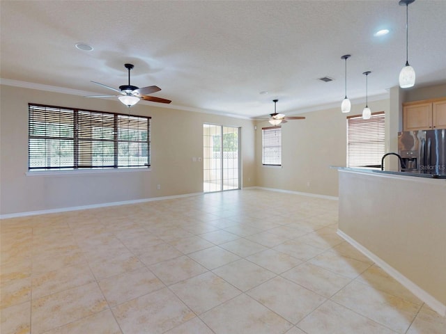 unfurnished living room featuring ceiling fan, ornamental molding, and baseboards
