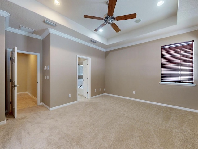 empty room with ornamental molding, a tray ceiling, visible vents, and light colored carpet