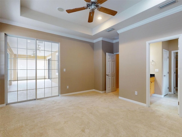spare room featuring ceiling fan, visible vents, ornamental molding, light carpet, and a tray ceiling