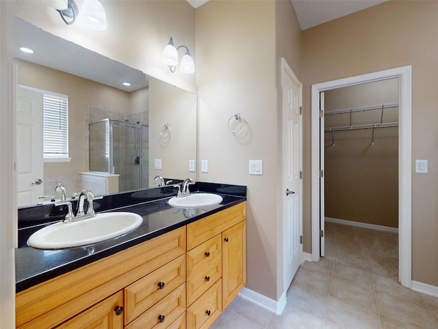 bathroom with double vanity, a sink, a walk in closet, and a shower stall