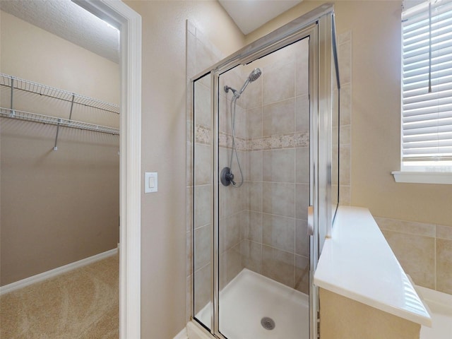 bathroom with a spacious closet and a shower stall