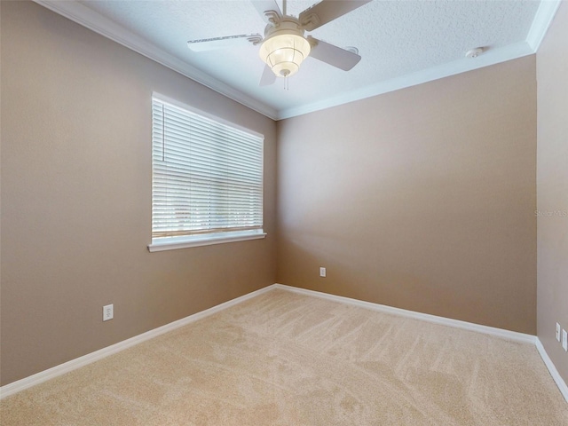 carpeted spare room with baseboards, ornamental molding, and ceiling fan