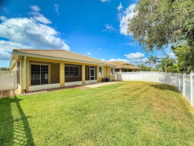 back of property with a tiled roof, a lawn, and stucco siding