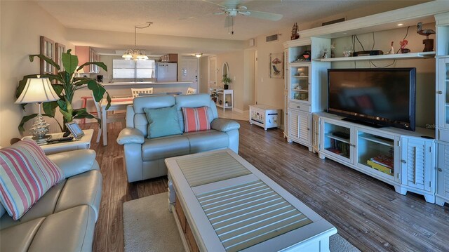 5499 Atlantic Unit 104, New Smyrna Beach, FL 32169 - living area with wood finished floors, visible vents, and ceiling fan with notable chandelier