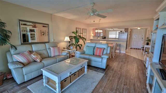 5499 Atlantic Unit 104, New Smyrna Beach, FL 32169 - living room with a textured ceiling, ceiling fan with notable chandelier, and wood finished floors
