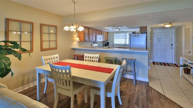 5499 Atlantic Unit 104, New Smyrna Beach, FL 32169 - dining room featuring an inviting chandelier, light wood-style flooring, a textured ceiling, and baseboards