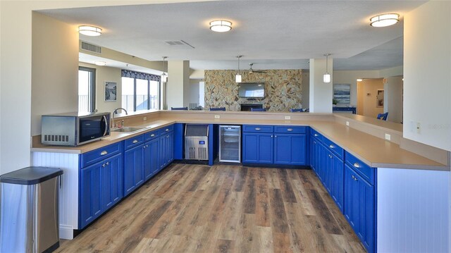 5499 Atlantic Unit 104, New Smyrna Beach, FL 32169 - kitchen featuring blue cabinets, beverage cooler, stainless steel microwave, and visible vents