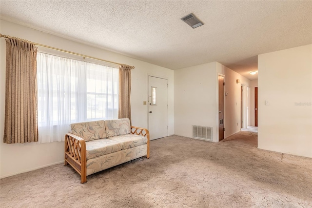 carpeted living area with a textured ceiling and visible vents