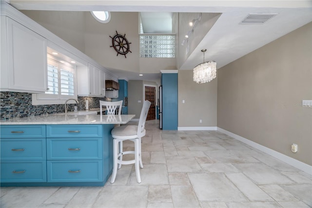 6260 S Atlantic Ave, New Smyrna Beach, FL 32169 - kitchen with tasteful backsplash, a breakfast bar, visible vents, blue cabinetry, and baseboards