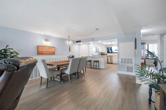 dining room with a textured ceiling, visible vents, and wood finished floors
