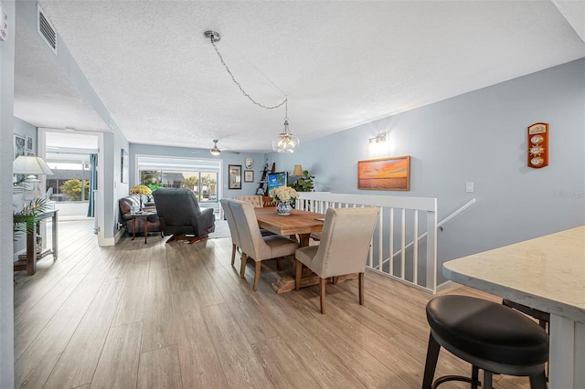dining area with baseboards, a textured ceiling, and light wood finished floors
