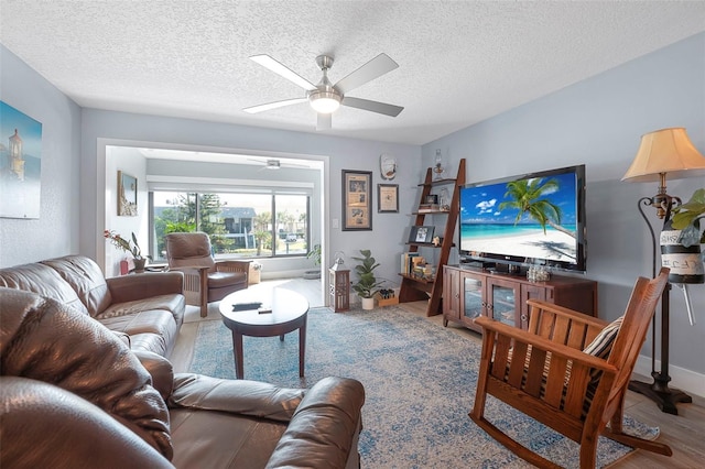 living area with a ceiling fan and a textured ceiling