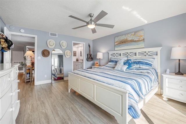 bedroom with light wood-type flooring, a ceiling fan, visible vents, a textured ceiling, and a spacious closet