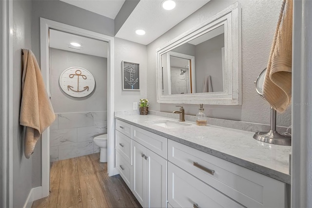 bathroom with recessed lighting, tile walls, vanity, toilet, and wood finished floors