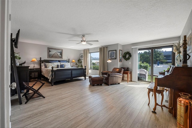 bedroom with a textured ceiling, light wood-style flooring, access to exterior, and multiple windows