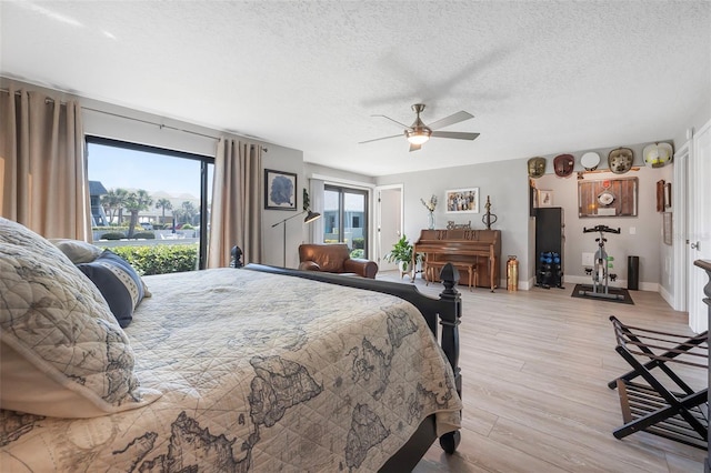 bedroom with access to outside, a ceiling fan, light wood-style flooring, baseboards, and a textured ceiling