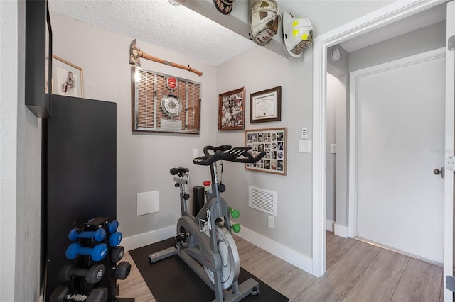 workout area featuring wood finished floors, visible vents, and baseboards