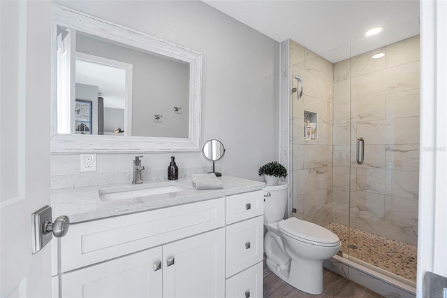 full bath with toilet, vanity, a shower stall, and wood finished floors