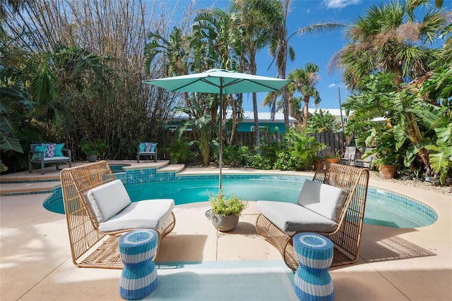 outdoor pool featuring a hot tub, a patio area, and fence