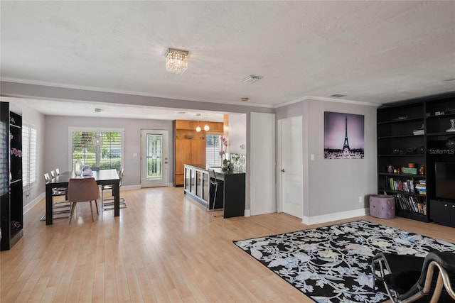 interior space with light wood finished floors, a notable chandelier, crown molding, baseboards, and a textured ceiling