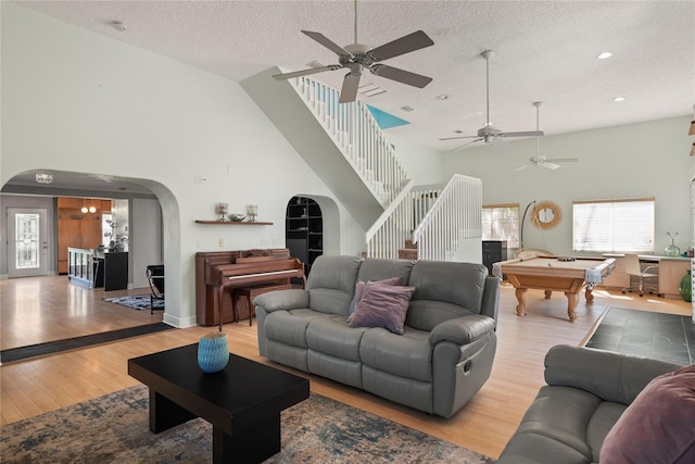 living room featuring light wood-style flooring, arched walkways, pool table, a ceiling fan, and high vaulted ceiling
