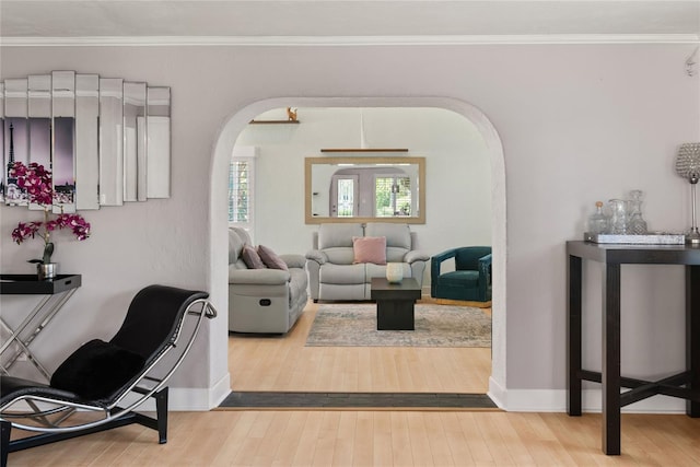living area with wood-type flooring, crown molding, arched walkways, and baseboards