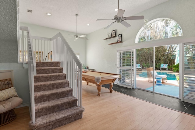 rec room with a wealth of natural light, wood finished floors, a ceiling fan, and a textured ceiling