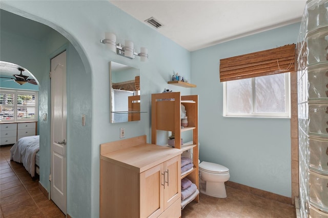 bathroom with visible vents, a shower with door, toilet, a ceiling fan, and tile patterned flooring