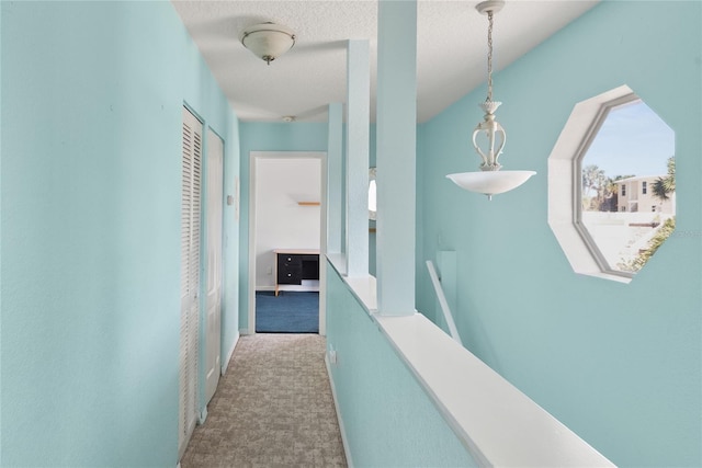 hall with an upstairs landing and carpet floors