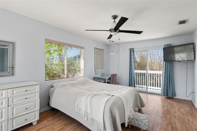 bedroom featuring access to exterior, visible vents, multiple windows, and wood finished floors