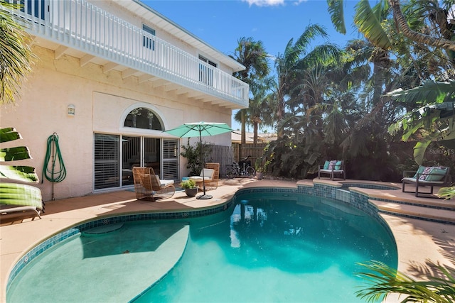 view of swimming pool with fence, a pool with connected hot tub, and a patio area