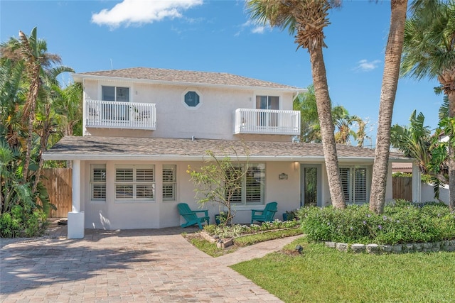 traditional-style home with fence, a balcony, and stucco siding