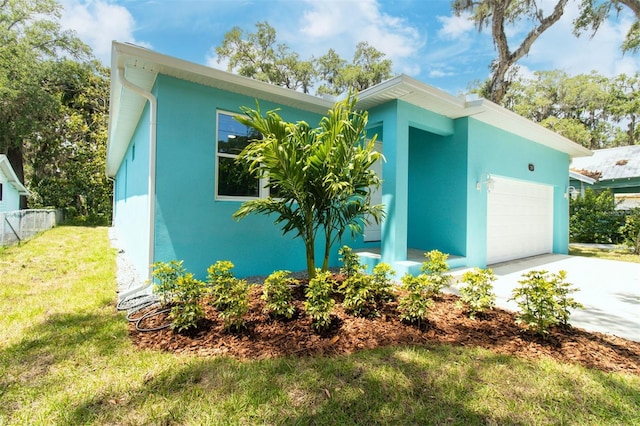 view of property exterior featuring a lawn, concrete driveway, stucco siding, and fence
