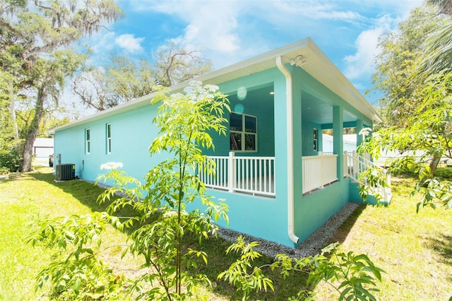 view of home's exterior with cooling unit, a yard, a porch, and stucco siding
